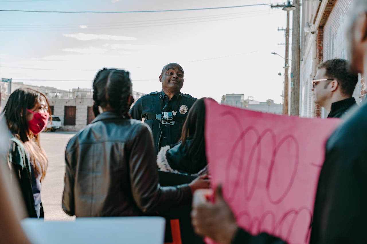 A diverse group of protesters peacefully engaging with a policeman outdoors.